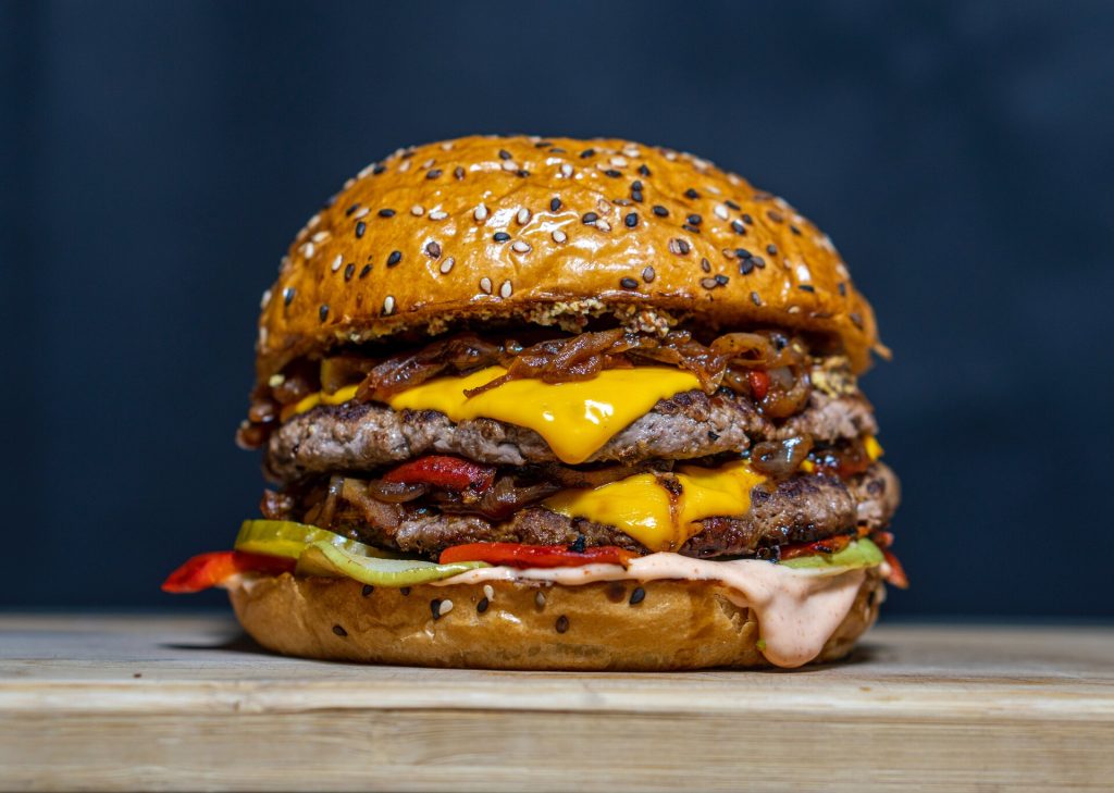 An appetizing burger with cheese, bacon, and onions.