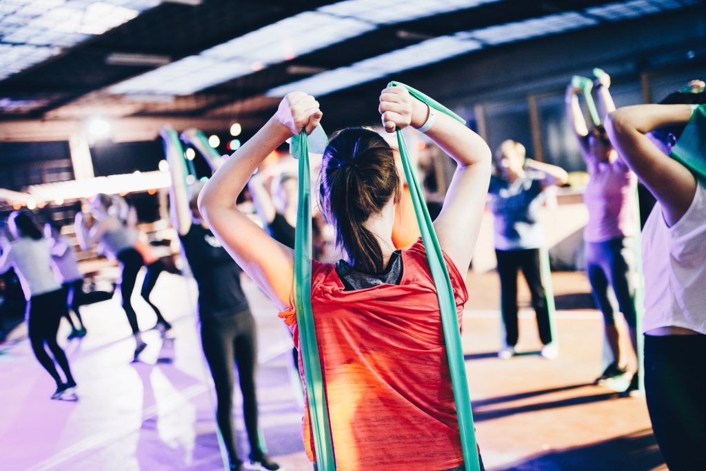 Diverse group of people exercising in a gym and using stretching bands.